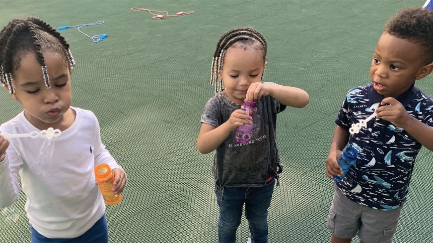 Three Training Wheels students a blowing bubbles.