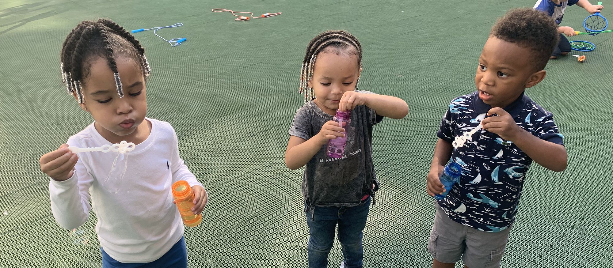Three Training Wheels students a blowing bubbles.